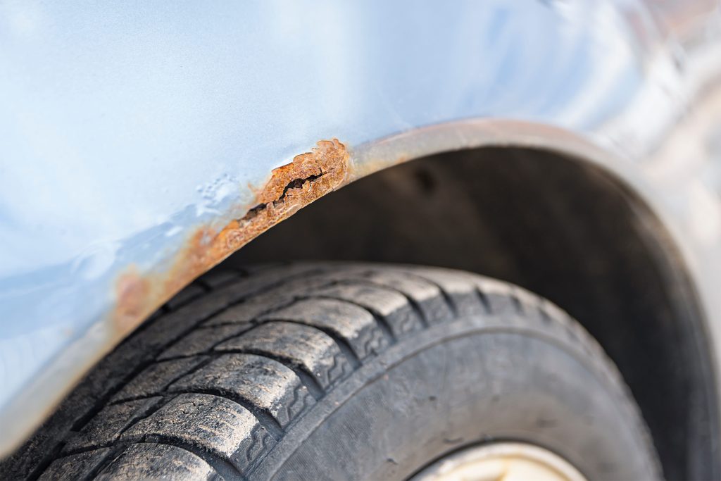 Corrosion of metal on a car body, close-up. Rust on the car door. Selective focus